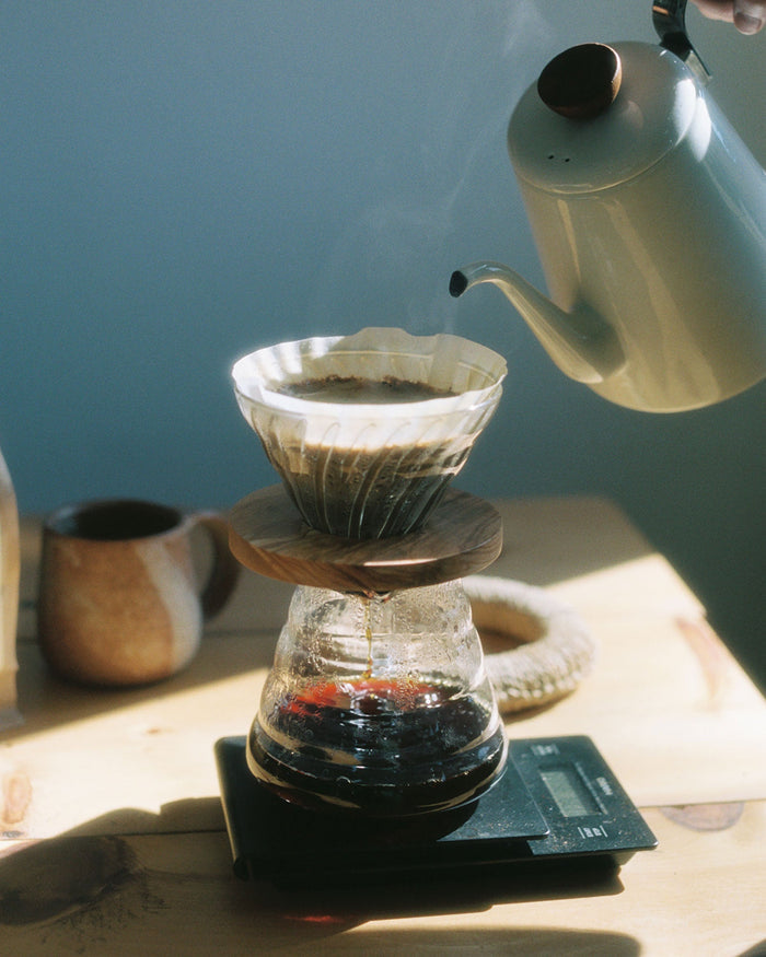 Black coffee and kitchen scale by Hario being used to make a pour over coffee