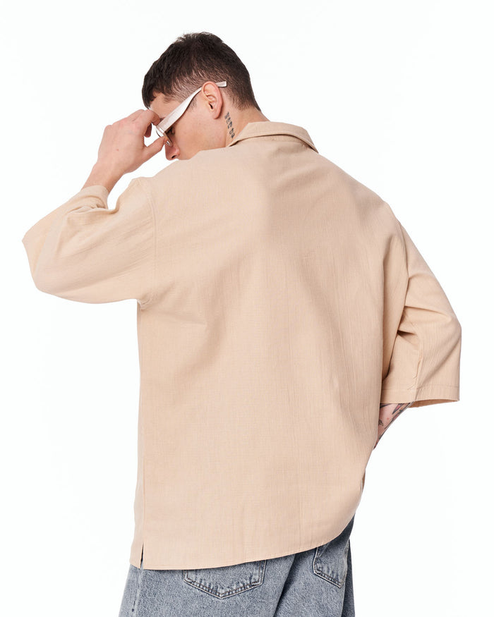 Martin Valen oversized beige linen shirt, rear view with subtle V-neck collar, side hem slit and casual light-wash jeans