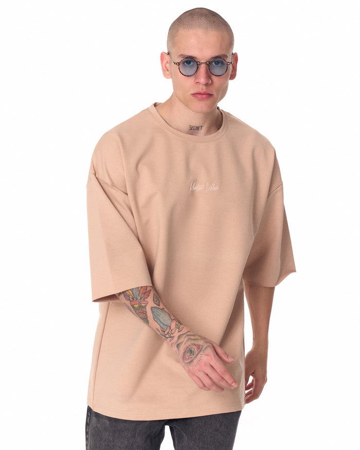 Martin Valen oversized beige Tβshirt worn by model, front view with round sunglasses and chest logo