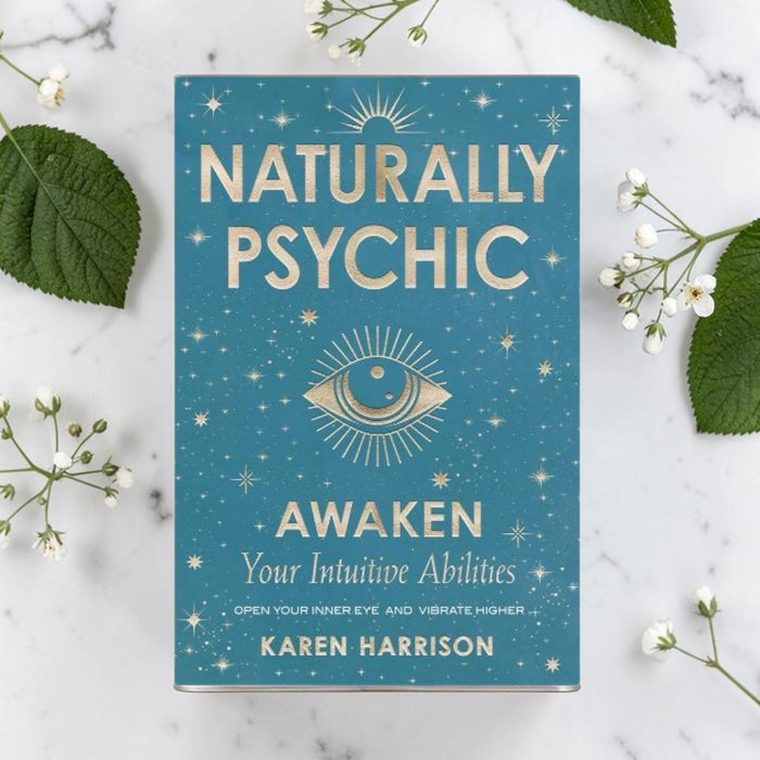 Book titled 'Naturally Psychic: Awaken Your Intuitive Abilities' by Karen Harrison on a marble surface with leaves and flowers.