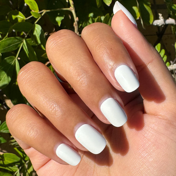Swan | Extra Short | Squoval - Tab Press-On showing hand with bright white press-on nails outdoors in natural sunlight