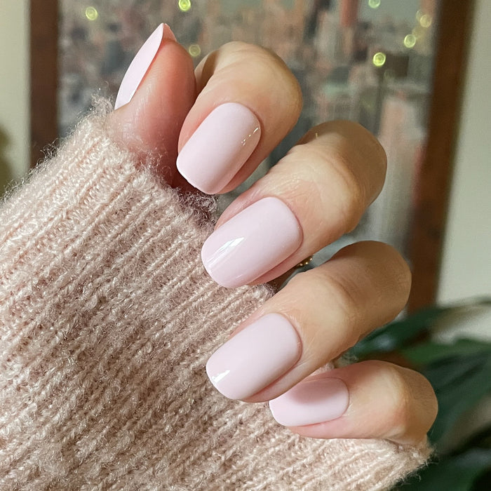 Tutu | Short | Squoval - Tab Press-On showing soft pastel pink false nails on hand wearing knitted sweater for easy mani.