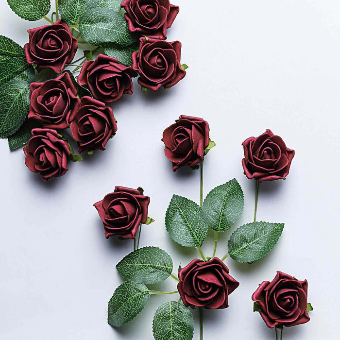 Red artificial roses with green leaves on a plain background.