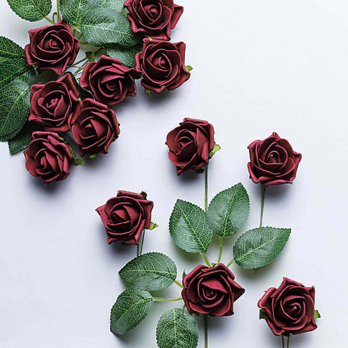Red artificial roses with green leaves on a plain background.