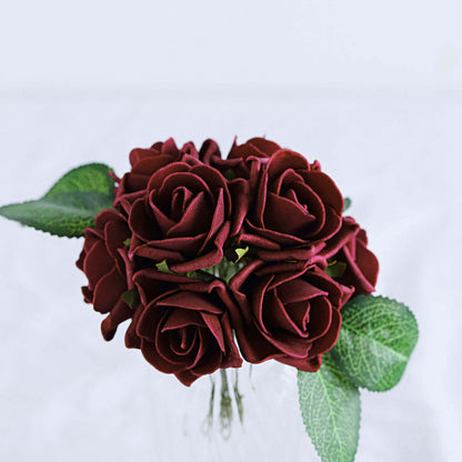 Red rose bouquet with green leaves on a plain backdrop.