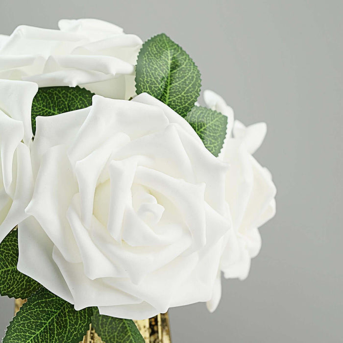 White artificial roses with green leaves in a decorative vase.
