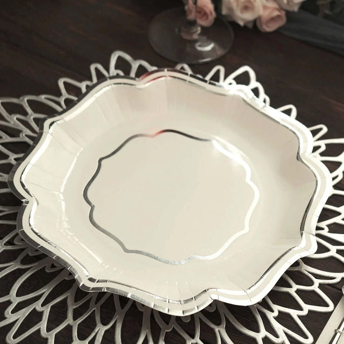 Elegant white scalloped plate with silver trim on decorative doily.