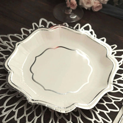 Elegant white scalloped plate with silver trim on decorative doily.