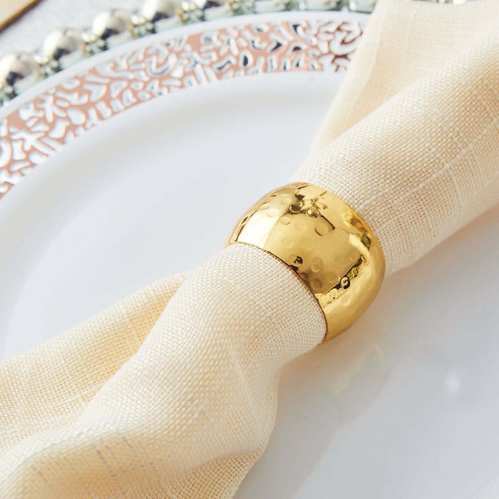 Gold napkin ring on a cream-colored napkin atop an elegant plate.