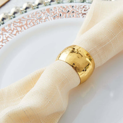 Gold napkin ring on a cream-colored napkin atop an elegant plate.