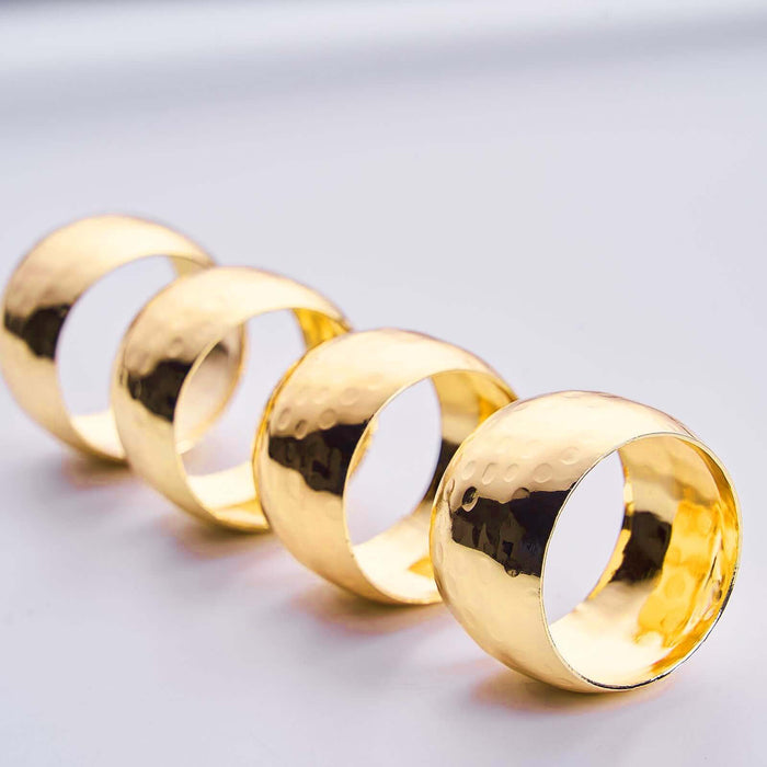 Set of four polished gold napkin rings with a hammered finish. #whtbkgd