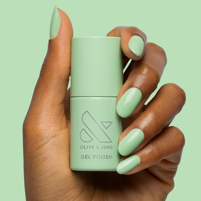 Hand holding Aced It - Gel bottle with nails painted in a soft pastel green for a fresh mani look