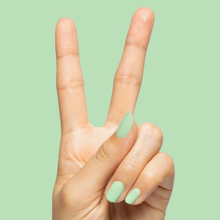 Hand showing peace sign with nails painted in pastel green using Aced It - Gel for fresh at-home mani look