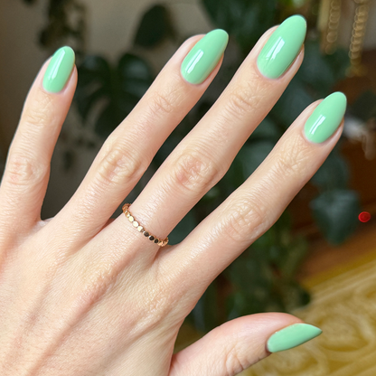 Hand with nails painted in glossy pastel green using Aced It - Gel for a smooth, long-lasting at-home manicure