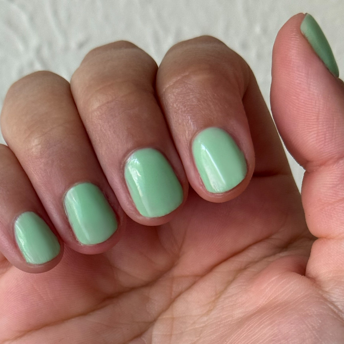 Close-up of hand with short nails polished in Aced It - Gel for a smooth, fresh pastel green manicure at home