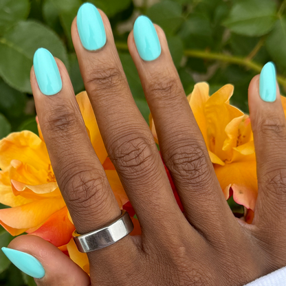 All Manis on Deck | Medium | Oval - Tab Press-On nails in bright aquatic blue-green shown on hand with orange roses background