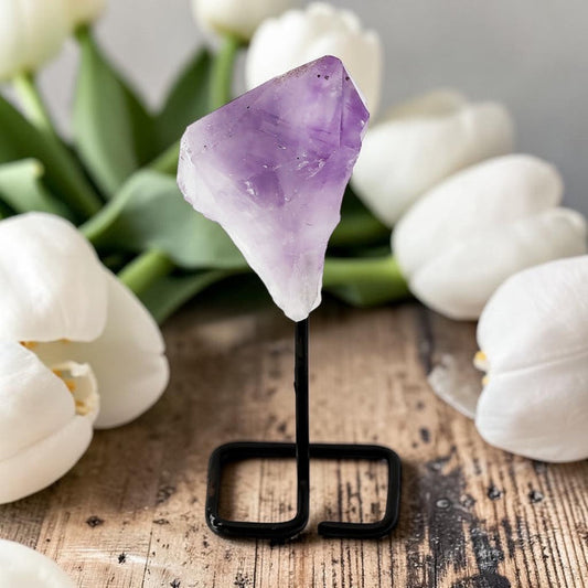 Amethyst crystal on a stand with white tulips in the background