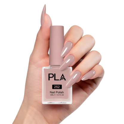 Hand holding a pink nail polish bottle with matching nails on a white background
