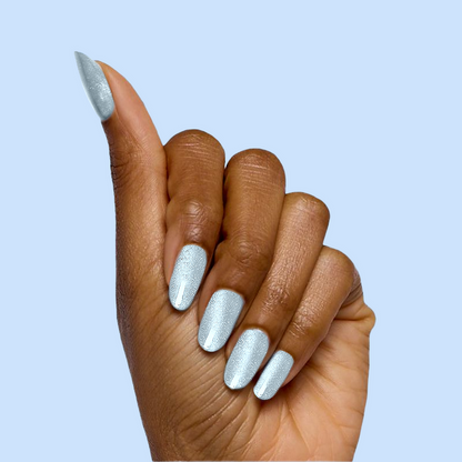 Hand showing nails painted with Aqua Velvet - Gel bright pastel blue magnetic gel polish against light blue background