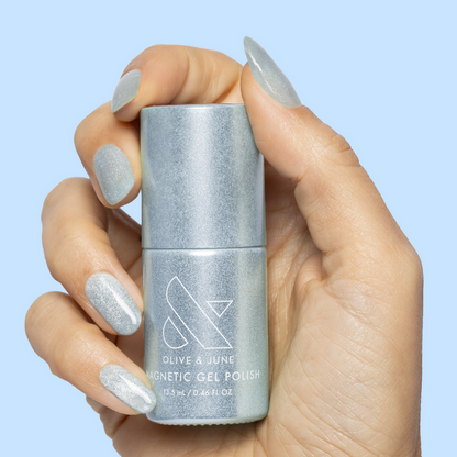 Hand holding Olive and June Aqua Velvet - Gel bottle with nails polished in shimmering pastel blue gel polish