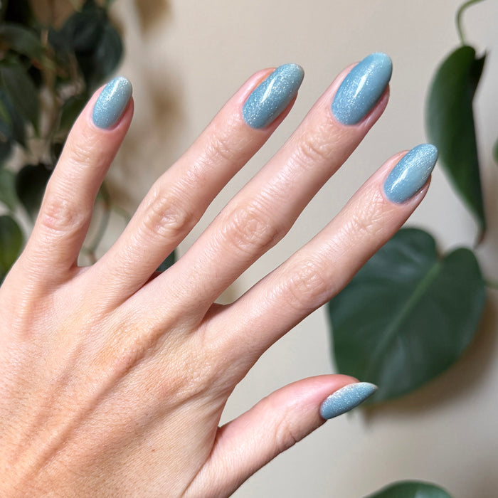 Hand with nails featuring Aqua Velvet - Gel bright pastel blue magnetic gel polish showing velvet texture under natural light