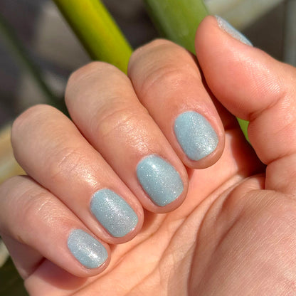 Hand with nails painted in Aqua Velvet - Gel bright pastel blue magnetic gel polish showing soft shimmer in natural light