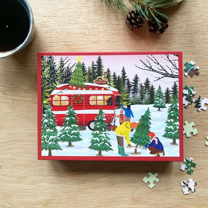 Experience the joyful spirit of a Christmas market adventure with the Caravan | 300 Piece Jigsaw Puzzle by ViSSEVASSE, featuring a heartwarming scene of people cutting a Christmas tree in a snowy forest near a red camper, surrounded by festive holiday decorations and loose puzzle pieces.