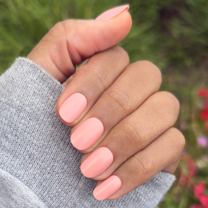Hand with short round nails in soft floral pink using Carnation | Short | Round - Tab Press-On for easy at-home mani
