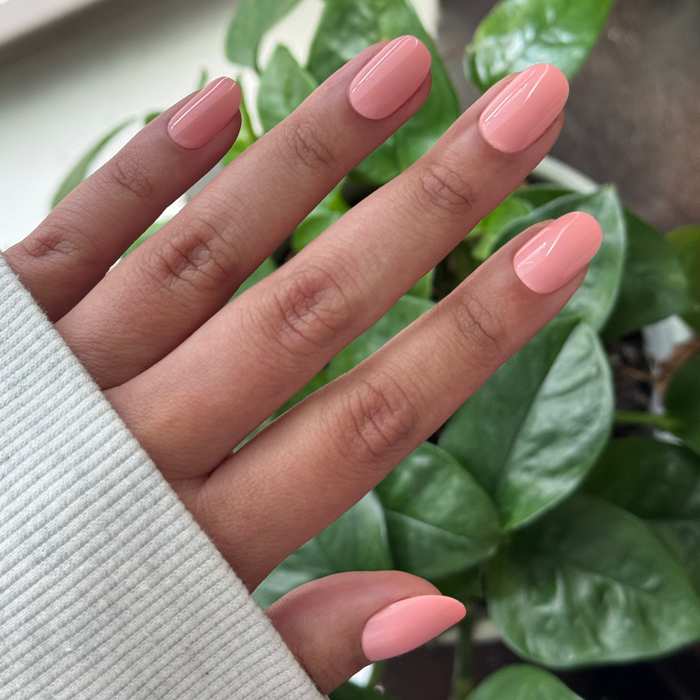 Close-up of hand with nails in soft floral pink using Carnation | Short | Round - Tab Press-On for an easy at-home manicure