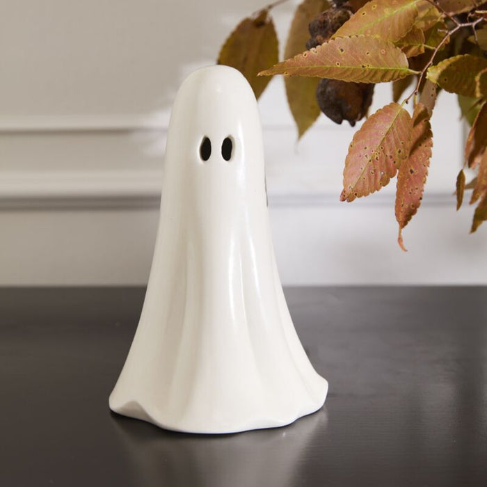 White ghost-shaped decorative item on a dark surface with a blurred background