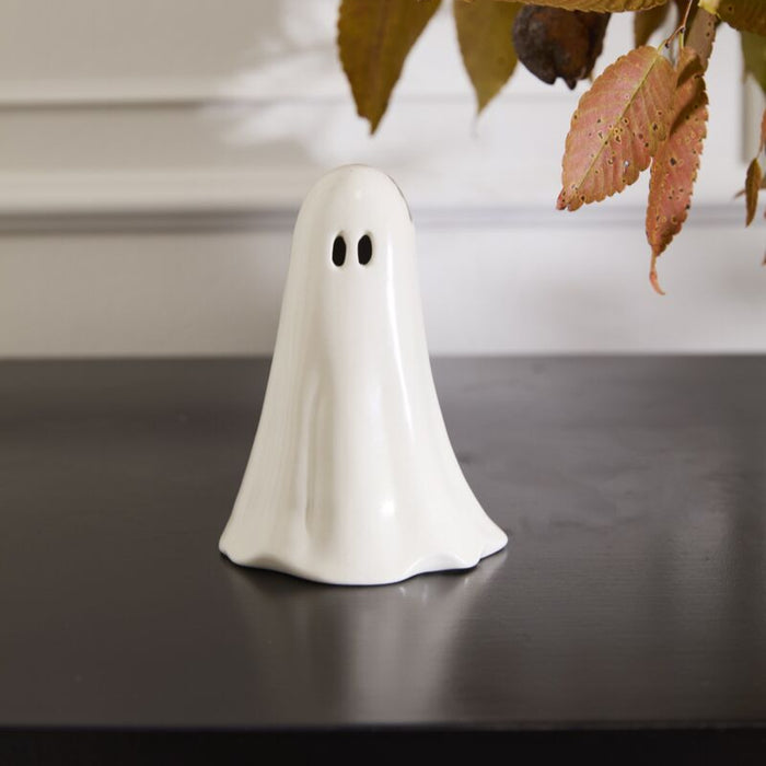 White ghost figurine on a dark surface with a blurred background