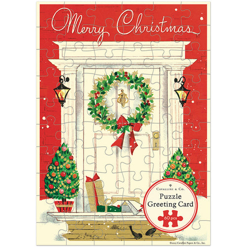 Introducing the “Christmas Home | 60 Piece Greeting Card Jigsaw Puzzle” from Cavallini & Co. This charming holiday greeting card features a beautifully illustrated front door decorated with a festive wreath, two glowing lanterns, Christmas trees, wrapped gifts, and a joyful ‘Merry Christmas’ message. With a 60-piece jigsaw puzzle included and highlighted on the front, this delightful keepsake is the perfect way to send festive cheer all season long.