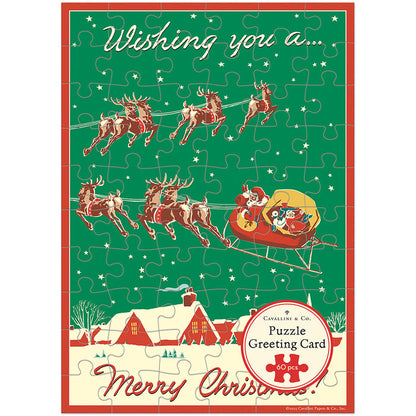 Send warm wishes this season with the Cavallini & Co. Christmas Reindeer | 60 Piece Greeting Card Jigsaw Puzzle, featuring Santa in a sleigh pulled by reindeer over a snowy village and the cheerful message “Wishing you a Merry Christmas!”.