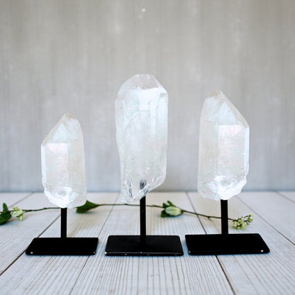Three Clear Quartz Point on Metal Base on stands against a white background
