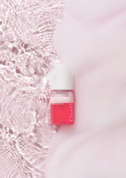 Red nail polish bottle with white cap on a light pink background