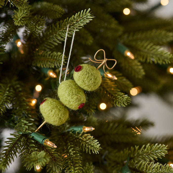 Decorative green ornaments on a Christmas tree with blurred lights in the background