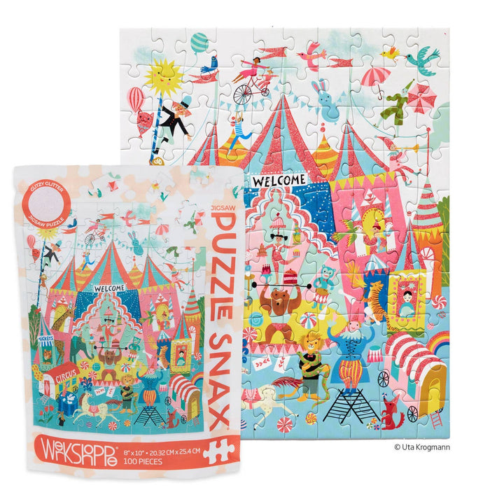 The WerkShoppe Colorful Circus 100 Piece Jigsaw Puzzle is assembled, with its vibrant box displayed in front, featuring acrobats, tents, animals, and performers.