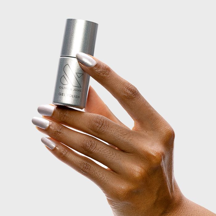Cosmic Silver - Gel metallic silver gel polish bottle held with matching shiny silver manicure on almond nails by Olive and June