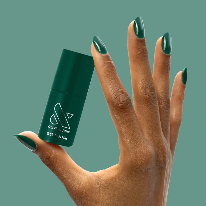 Fiddlefig - Gel polish bottle held by hand with deep leafy green nails for a fresh, long-lasting manicure by Olive and June