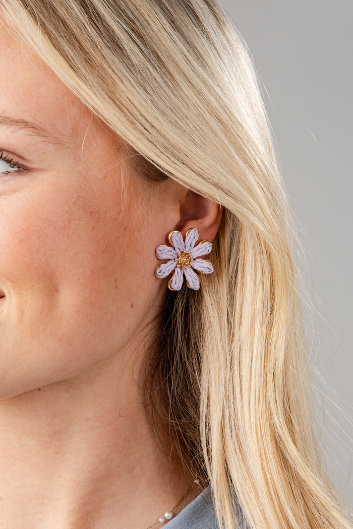 Close-up of a woman wearing a floral earring with a plain background
