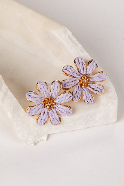 Purple flower earrings on a white fabric background