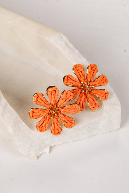 Orange flower-shaped earrings on a white fabric background