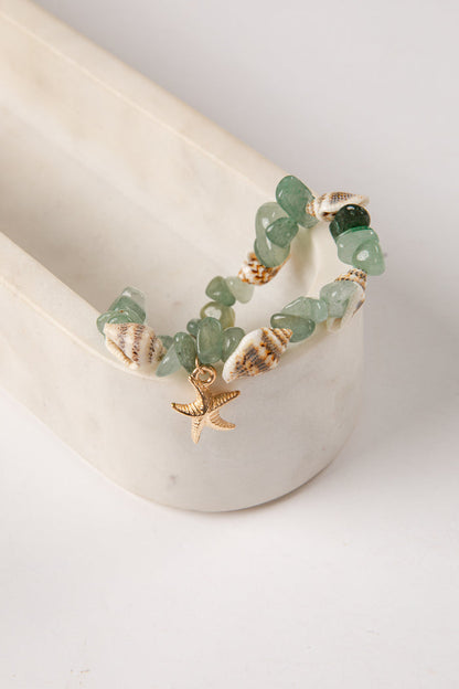 Bracelet with green beads and starfish charm on a white surface