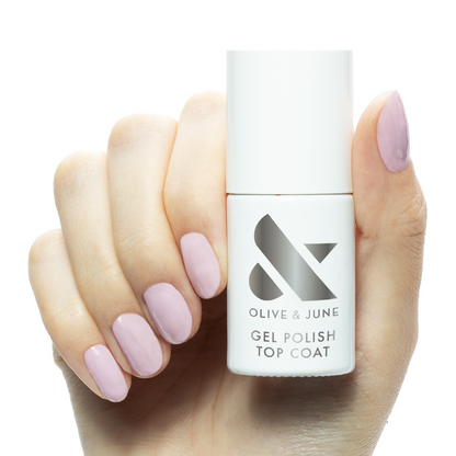 Hand holding Gel Top Coat bottle with glossy soft pink gel polished nails for at home manicure care