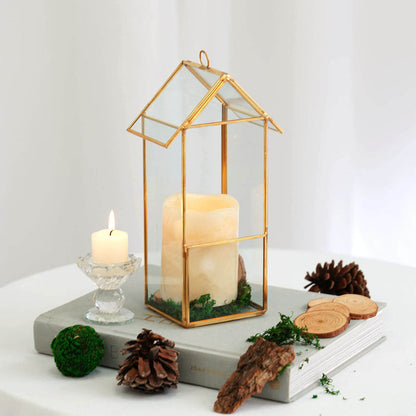 Gold-framed glass lantern with candle, surrounded by natural decor elements.