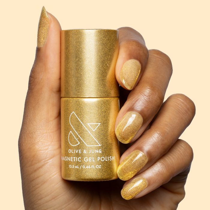 Hand holding Golden Velvet - Gel bottle with nails polished in shimmering golden bronze magnetic gel manicure
