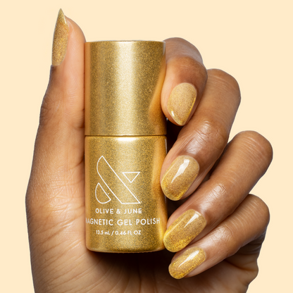 Hand holding Golden Velvet - Gel bottle with nails polished in shimmering golden bronze magnetic gel manicure