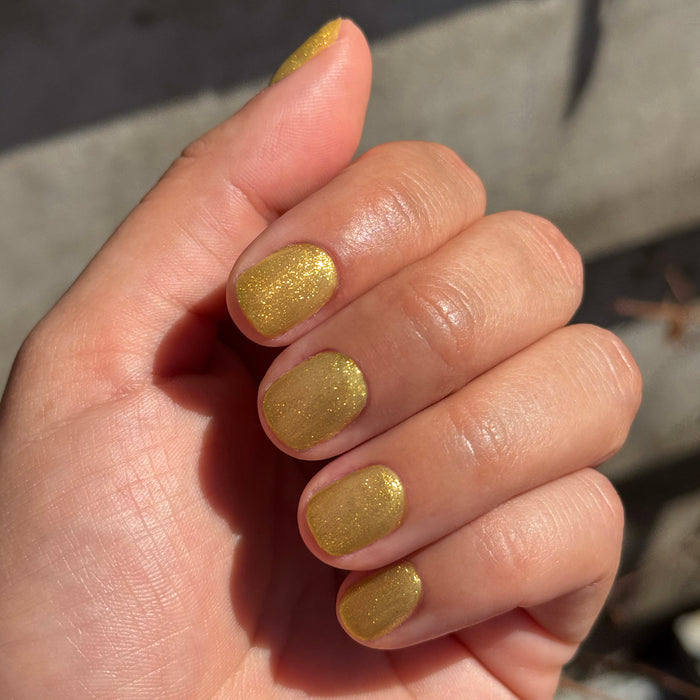 Hand with nails painted in Golden Velvet - Gel showing sparkling golden bronze manicure with magnetic gel polish effect