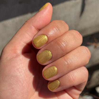 Hand with nails painted in Golden Velvet - Gel showing sparkling golden bronze manicure with magnetic gel polish effect
