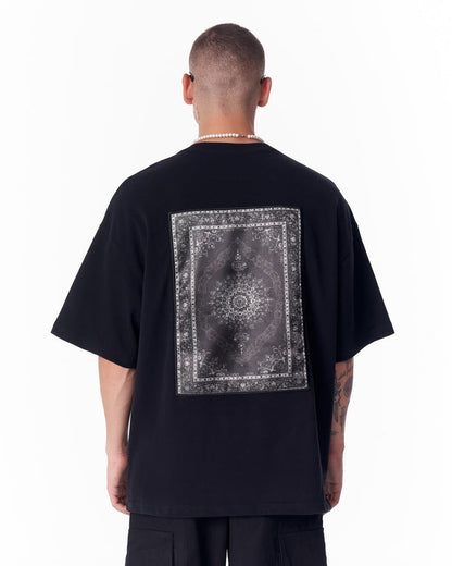 Martin Valen black oversized T‑shirt back view with large gothic rectangular applique patch and visible pearl necklace